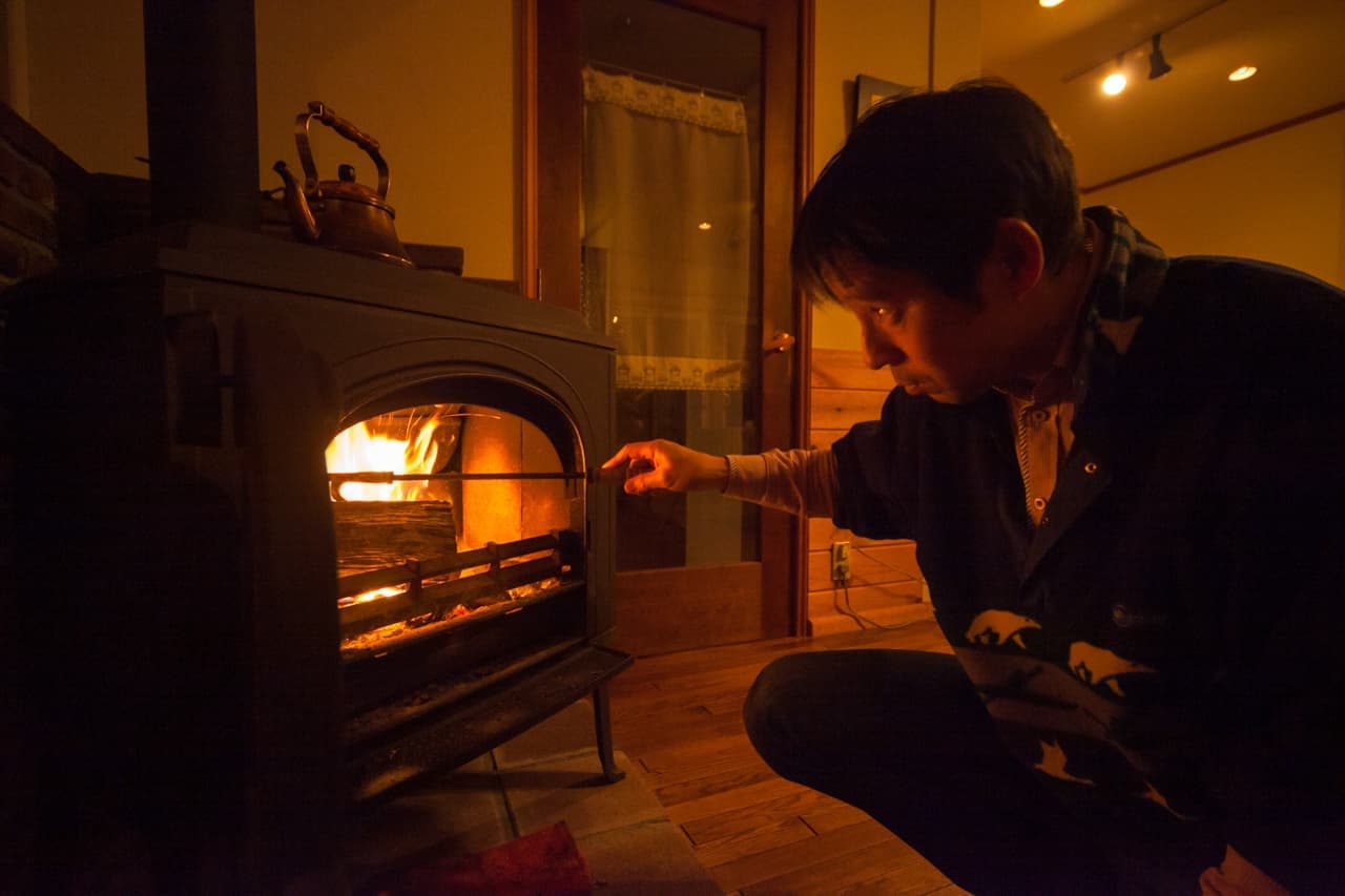 薪ストーブの火の様子を見るオーナー
